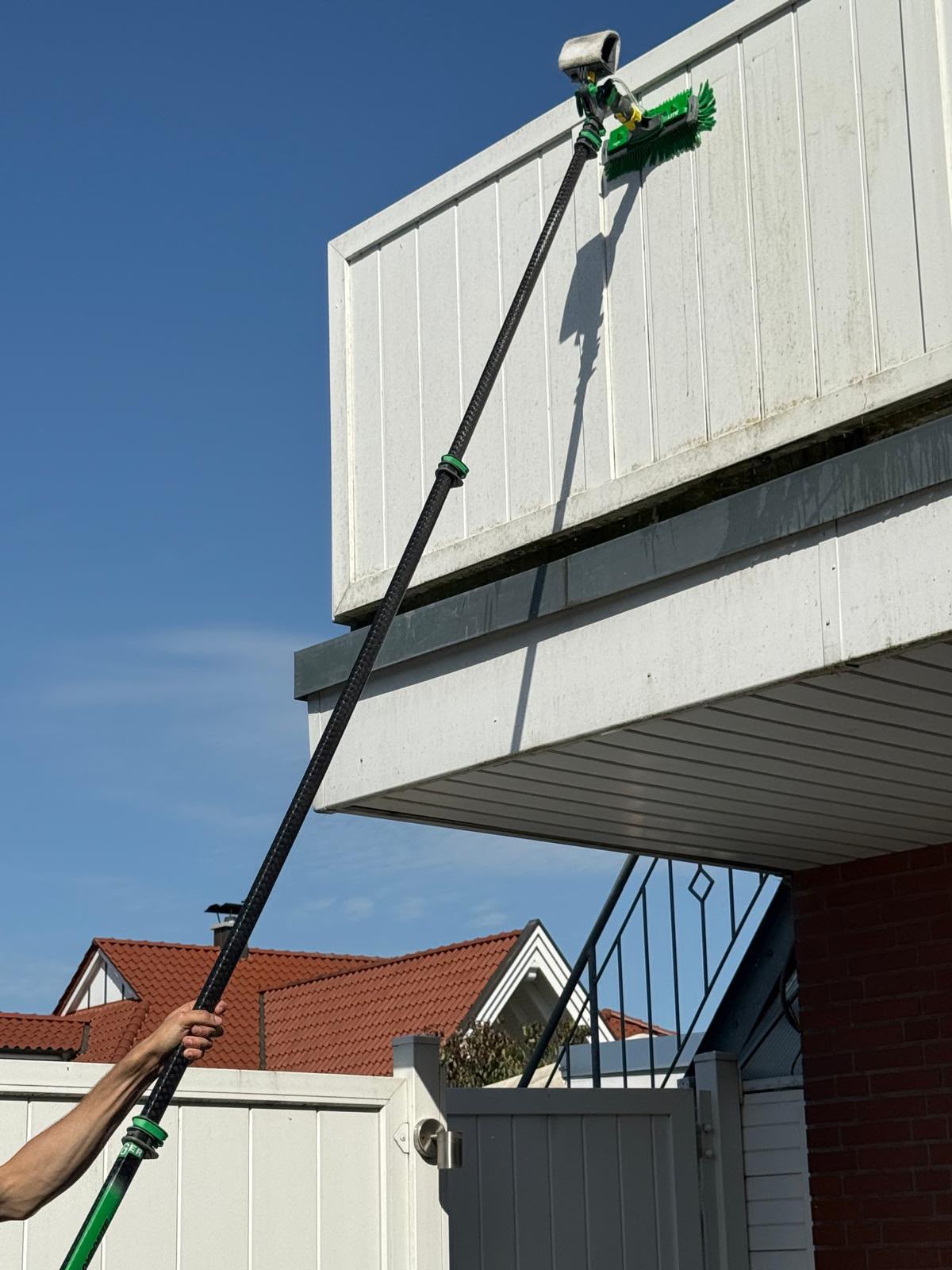 DALE Mitarbeiter reinigt eine Fassade mit der Teleskopstange